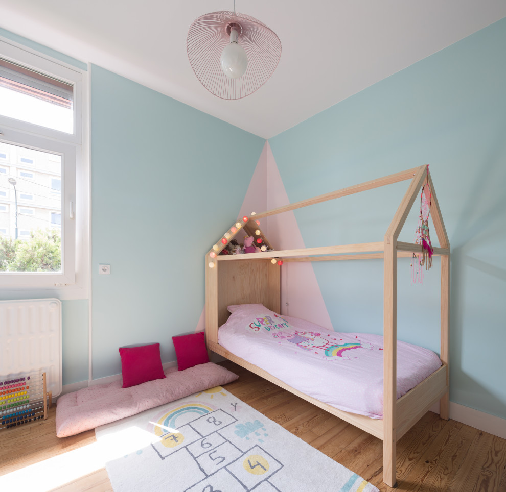 Diseño de dormitorio infantil de 4 a 10 años actual de tamaño medio con paredes azules y suelo de madera clara