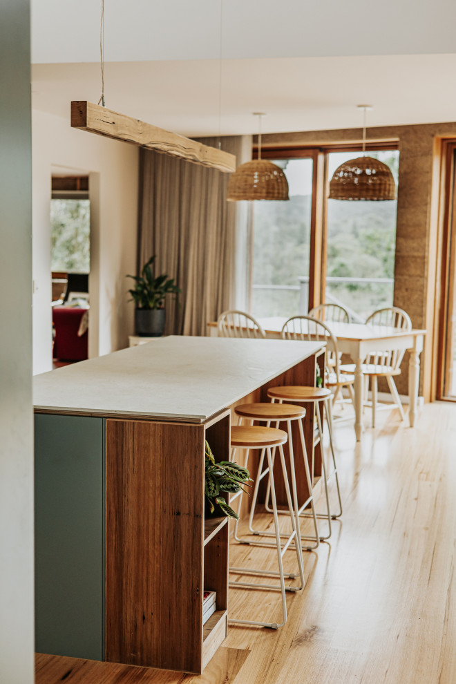 Photo of a mid-sized country open plan kitchen in Melbourne with a double-bowl sink, green cabinets, white splashback, porcelain splashback, black appliances, with island and vaulted.