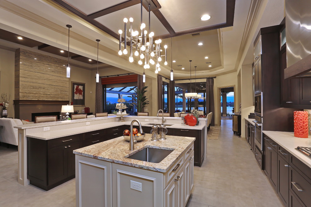 Design ideas for a large contemporary l-shaped open plan kitchen in Tampa with an undermount sink, flat-panel cabinets, dark wood cabinets, granite benchtops, beige splashback, glass tile splashback, panelled appliances, travertine floors and with island.