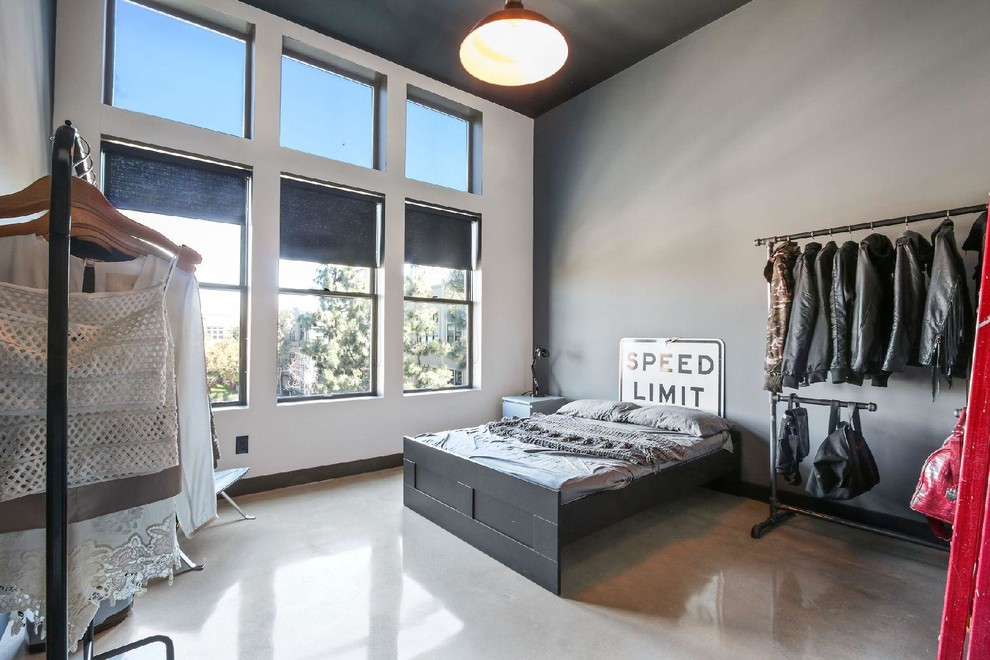 Mid-sized industrial guest bedroom in Orange County with grey walls, concrete floors and grey floor.