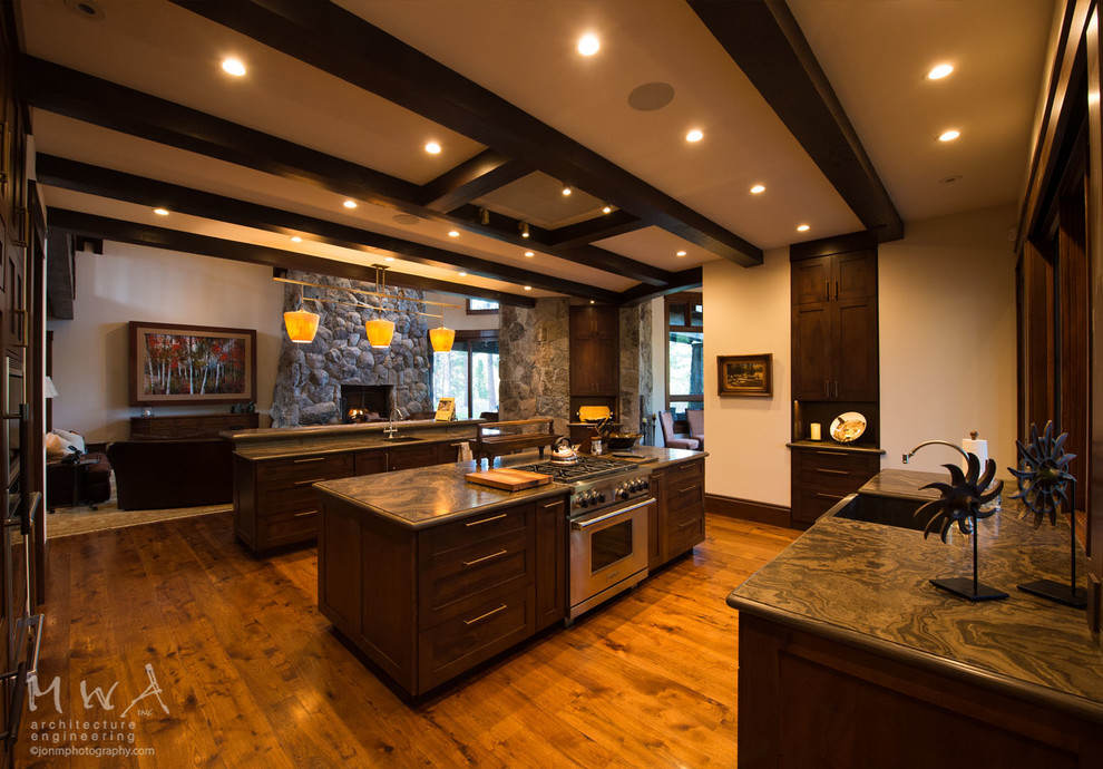 Expansive transitional l-shaped open plan kitchen in Other with a farmhouse sink, shaker cabinets, dark wood cabinets, dark hardwood floors, multiple islands, stainless steel appliances, brown floor and grey benchtop.