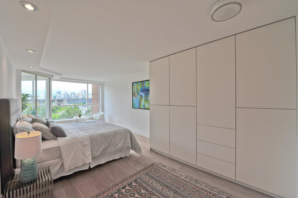 Photo of a mid-sized modern master bedroom in Vancouver with white walls and light hardwood floors.