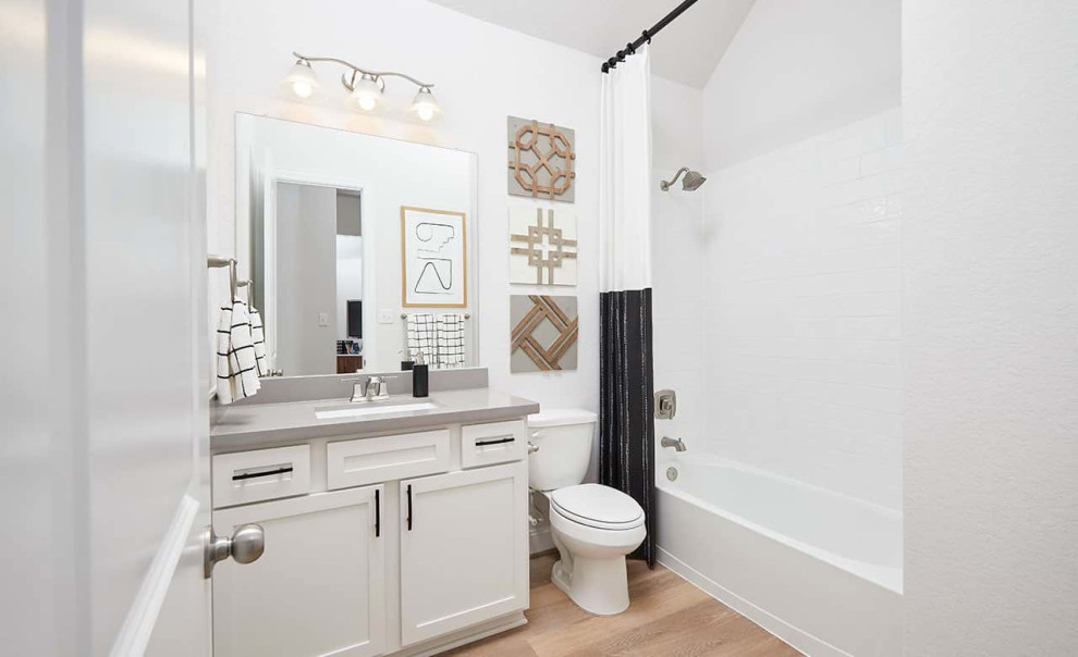 Contemporary bathroom in Other with recessed-panel cabinets, white cabinets, an alcove tub, a shower/bathtub combo, white tile, laminate floors, brown floor, a shower curtain, grey benchtops, a single vanity, a built-in vanity and an undermount sink.