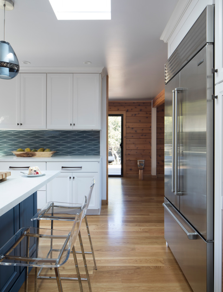 サンフランシスコにある高級な中くらいなコンテンポラリースタイルのおしゃれなキッチン (エプロンフロントシンク、白いキャビネット、青いキッチンパネル、シルバーの調理設備、無垢フローリング、ベージュの床、白いキッチンカウンター、シェーカースタイル扉のキャビネット、クオーツストーンカウンター、セラミックタイルのキッチンパネル) の写真
