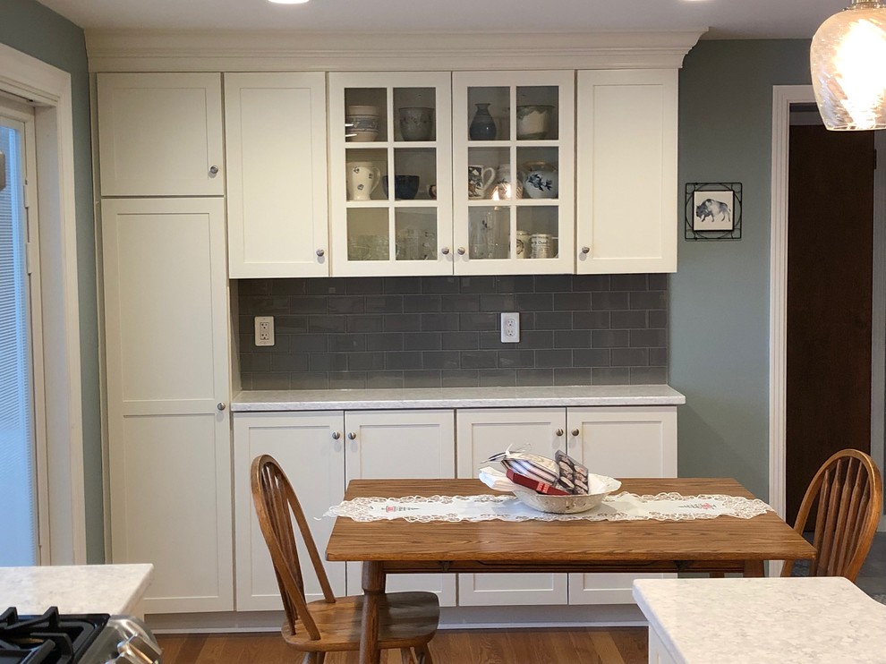 Photo of a large transitional l-shaped separate kitchen in New York with an undermount sink, shaker cabinets, white cabinets, quartzite benchtops, grey splashback, glass tile splashback, stainless steel appliances, medium hardwood floors, with island, multi-coloured floor and white benchtop.