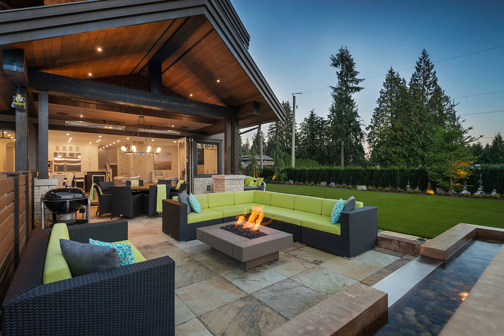Design ideas for an expansive arts and crafts backyard patio in Vancouver with a fire feature, tile and a roof extension.
