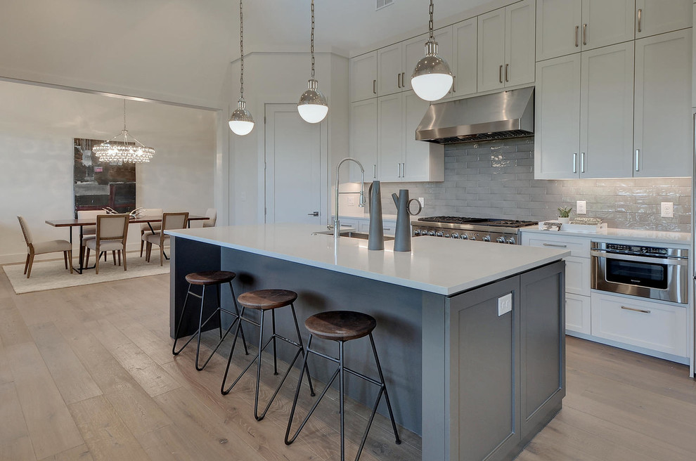 Design ideas for a modern kitchen in Austin with shaker cabinets, white cabinets, quartzite benchtops, grey splashback, stainless steel appliances and medium hardwood floors.