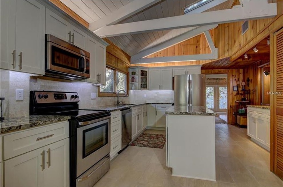 This is an example of a mid-sized traditional galley eat-in kitchen in Tampa with an undermount sink, shaker cabinets, white cabinets, granite benchtops, beige splashback, travertine splashback, stainless steel appliances, ceramic floors, with island and beige floor.