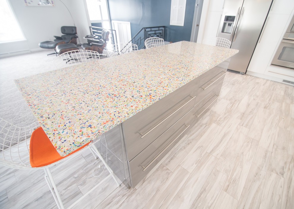 Mid-sized modern l-shaped eat-in kitchen in Other with a single-bowl sink, recycled glass benchtops, blue splashback, glass tile splashback, stainless steel appliances, ceramic floors and with island.