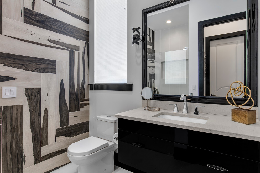 Photo of a small modern 3/4 bathroom in Orlando with flat-panel cabinets, black cabinets, an alcove shower, a two-piece toilet, black and white tile, glass tile, white walls, porcelain floors, a drop-in sink and engineered quartz benchtops.