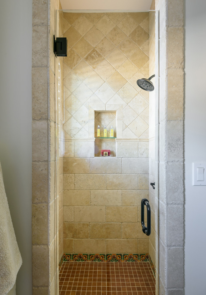 Design ideas for a mid-sized mediterranean bathroom in Jacksonville with flat-panel cabinets, dark wood cabinets, an alcove shower, a two-piece toilet, white tile, travertine, white walls, travertine floors, an undermount sink, marble benchtops, beige floor, a hinged shower door and beige benchtops.