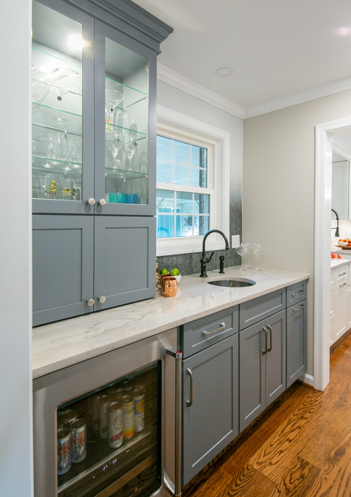 Photo of a large classic kitchen pantry in Baltimore with a belfast sink, shaker cabinets, quartz worktops, stainless steel appliances, medium hardwood flooring, an island and white worktops.