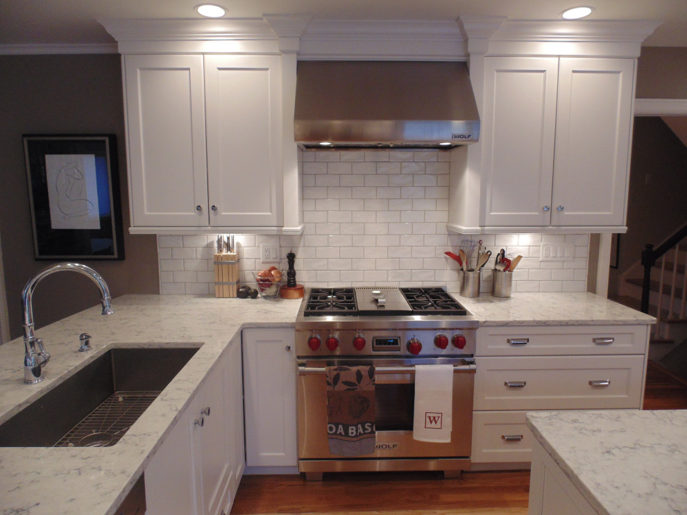 Eat-in kitchen - large transitional u-shaped medium tone wood floor and brown floor eat-in kitchen idea with an undermount sink, recessed-panel cabinets, white cabinets, quartz countertops, white backsplash, subway tile backsplash, stainless steel appliances, an island and white countertops
