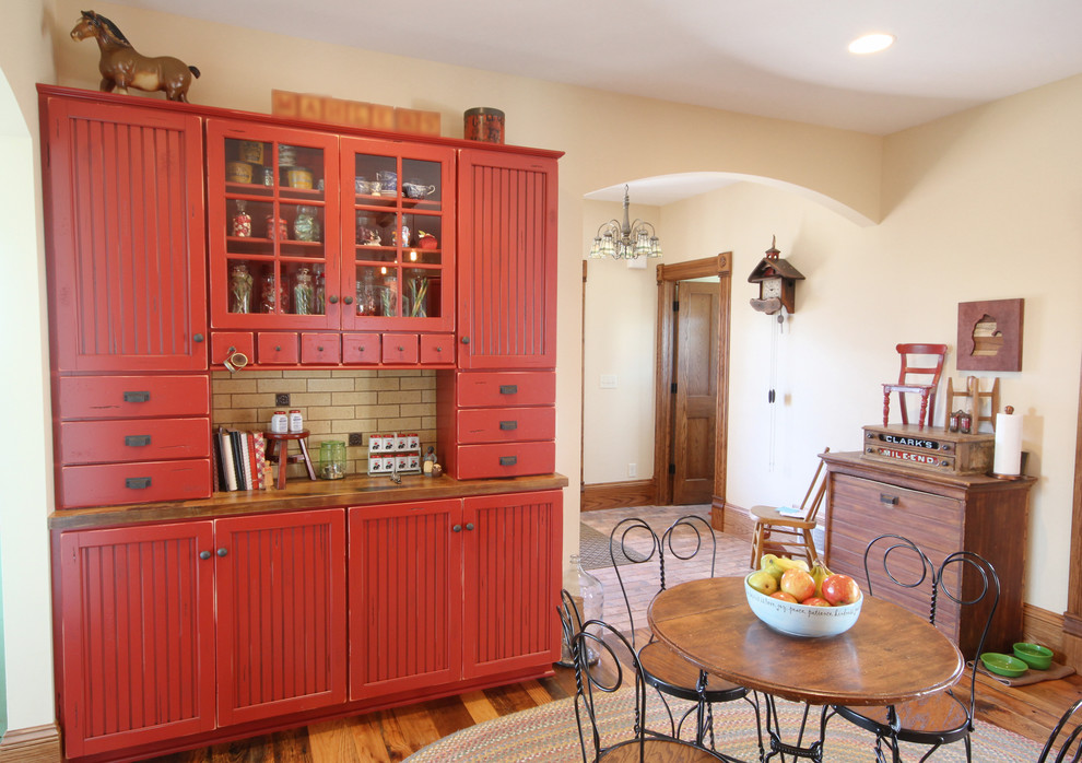 Inspiration for a large country l-shaped eat-in kitchen in Grand Rapids with red cabinets, wood benchtops, beige splashback, subway tile splashback, medium hardwood floors, with island, a farmhouse sink, recessed-panel cabinets and stainless steel appliances.