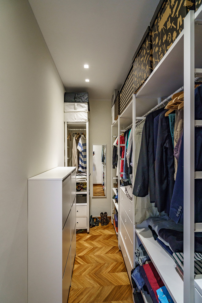 Mid-sized modern gender-neutral walk-in wardrobe in Florence with open cabinets, white cabinets, light hardwood floors and brown floor.