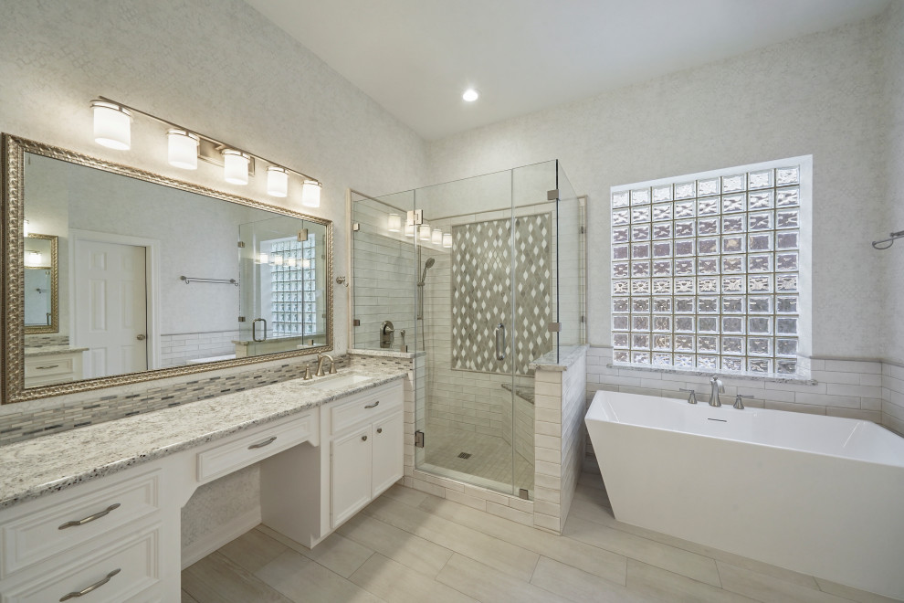 ヒューストンにある高級な中くらいなコンテンポラリースタイルのおしゃれなマスターバスルーム (レイズドパネル扉のキャビネット、白いキャビネット、置き型浴槽、コーナー設置型シャワー、分離型トイレ、白いタイル、セラミックタイル、白い壁、セラミックタイルの床、アンダーカウンター洗面器、御影石の洗面台、白い床、開き戸のシャワー、グレーの洗面カウンター、シャワーベンチ、洗面台2つ、造り付け洗面台、格子天井、壁紙) の写真