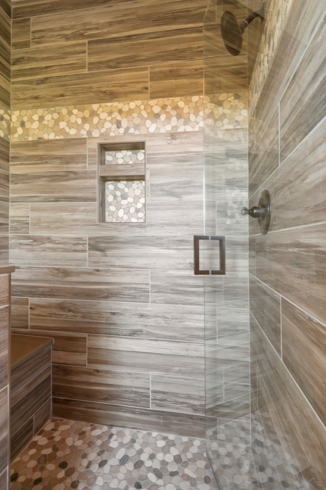 This is an example of a large country master bathroom in Cleveland with shaker cabinets, medium wood cabinets, an alcove tub, a corner shower, a two-piece toilet, multi-coloured tile, porcelain tile, beige walls, dark hardwood floors, an undermount sink, engineered quartz benchtops, brown floor, a hinged shower door, beige benchtops, a niche, a double vanity and a built-in vanity.