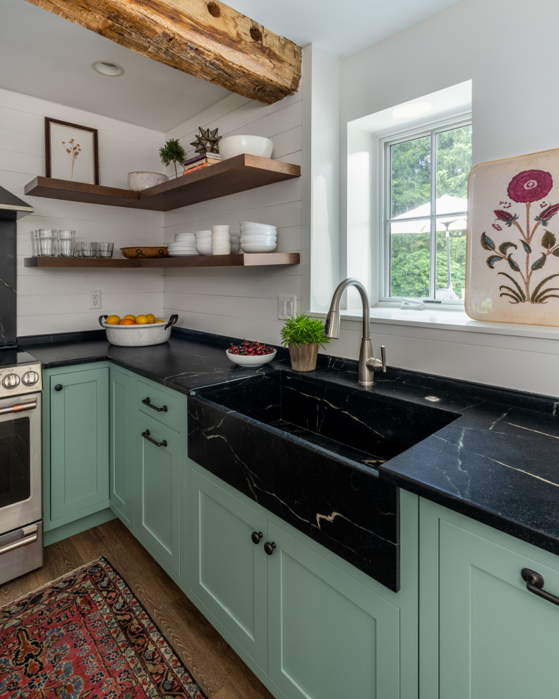 Inspiration for a small farmhouse l-shaped laminate floor and brown floor enclosed kitchen remodel in Philadelphia with a farmhouse sink, shaker cabinets, green cabinets, soapstone countertops, black backsplash, stone slab backsplash, stainless steel appliances, an island and black countertops