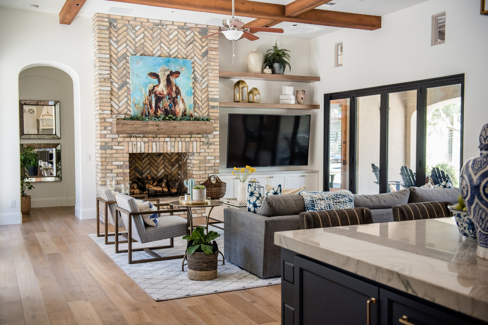 Expansive eclectic open concept family room in Phoenix with white walls, medium hardwood floors, a standard fireplace, a brick fireplace surround and a wall-mounted tv.