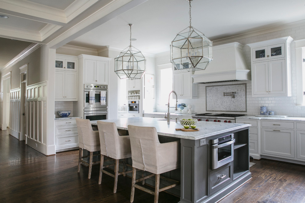 Inspiration for a traditional open plan kitchen in Atlanta with a farmhouse sink, white splashback, subway tile splashback, stainless steel appliances, dark hardwood floors, with island, shaker cabinets, white cabinets and marble benchtops.