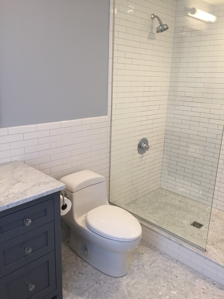 Photo of a mid-sized traditional master bathroom in Providence with shaker cabinets, grey cabinets, an open shower, a one-piece toilet, white tile, ceramic tile, grey walls, mosaic tile floors, an undermount sink, marble benchtops, grey floor, an open shower and grey benchtops.