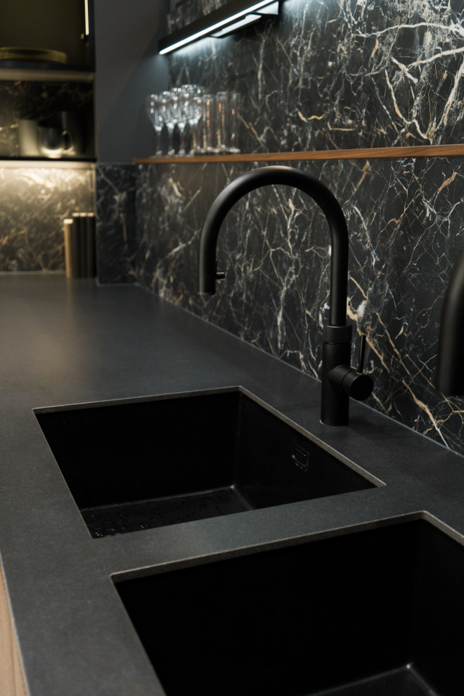 Inspiration for a medium sized modern l-shaped open plan kitchen in London with a built-in sink, glass-front cabinets, black cabinets, marble worktops, black splashback, stone slab splashback, black appliances, porcelain flooring, an island, grey floors and black worktops.