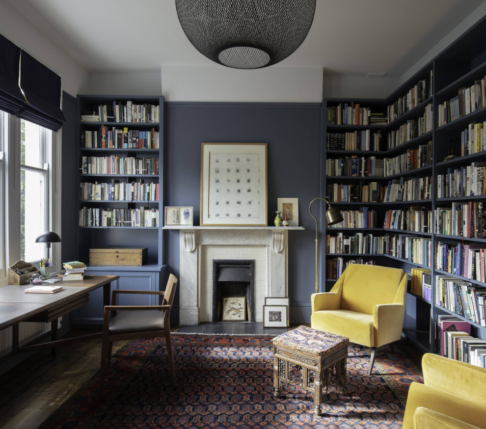 Transitional study room in London with white walls, a standard fireplace and a freestanding desk.