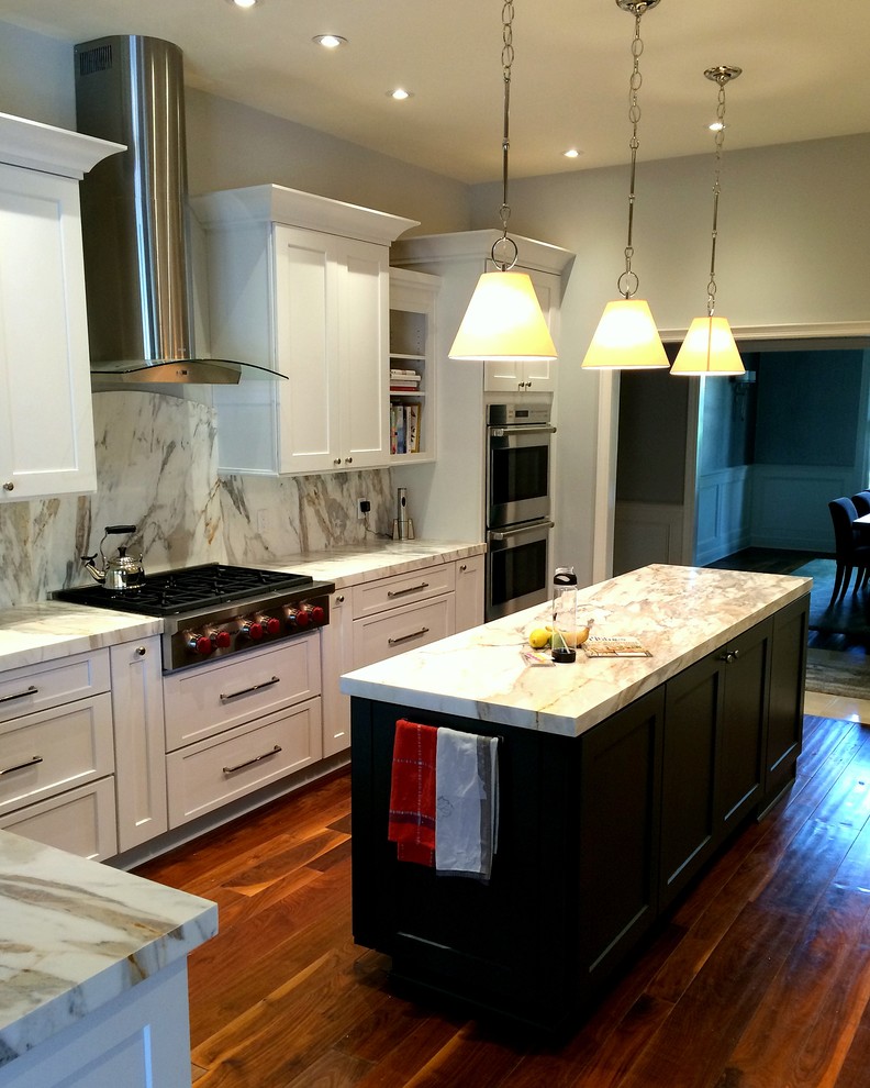This is an example of a mid-sized traditional u-shaped eat-in kitchen in Tampa with shaker cabinets, white cabinets, marble benchtops, multi-coloured splashback, stone slab splashback, stainless steel appliances, with island, a double-bowl sink, medium hardwood floors and brown floor.