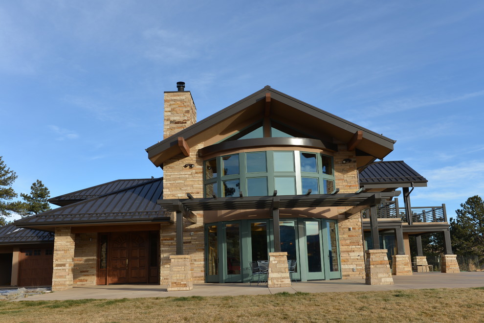 Expansive country two-storey brown house exterior in Denver with stone veneer, a clipped gable roof and a metal roof.