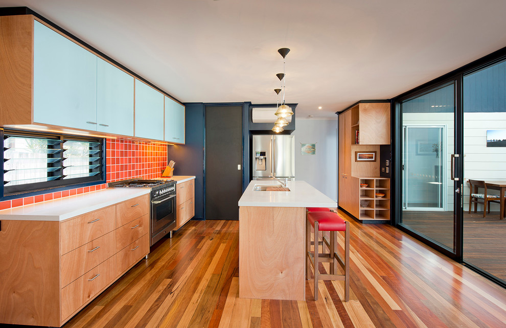 Photo of a contemporary u-shaped kitchen in Brisbane with an undermount sink, flat-panel cabinets, light wood cabinets, red splashback, ceramic splashback, stainless steel appliances, medium hardwood floors and with island.