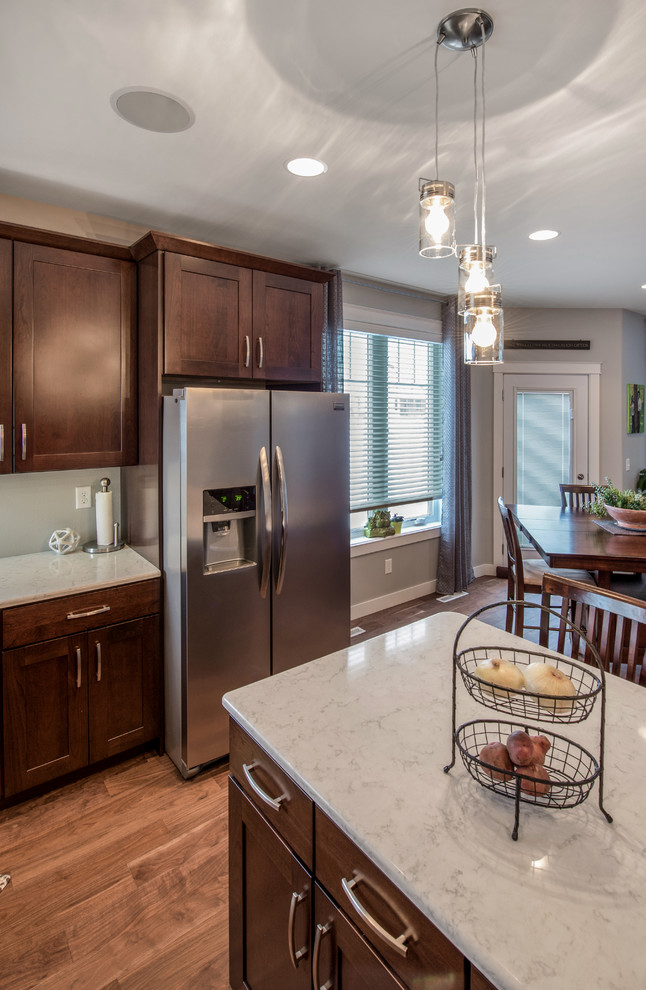 This is an example of a large country u-shaped open plan kitchen in Other with a double-bowl sink, shaker cabinets, dark wood cabinets, granite benchtops, stainless steel appliances, medium hardwood floors and with island.