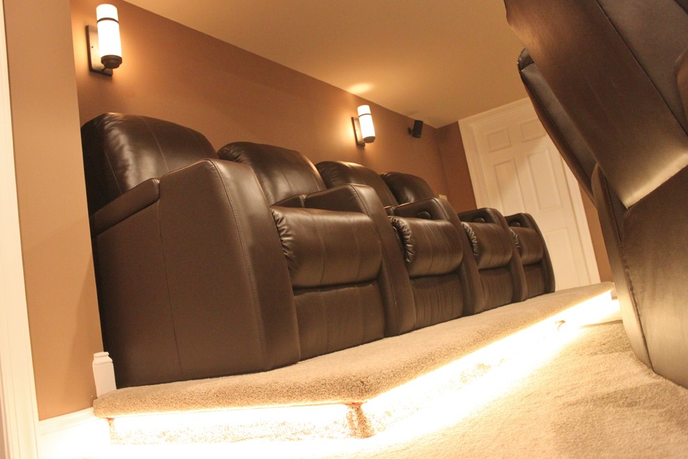 Photo of a mid-sized traditional enclosed home theatre in Philadelphia with brown walls, carpet, a projector screen and beige floor.