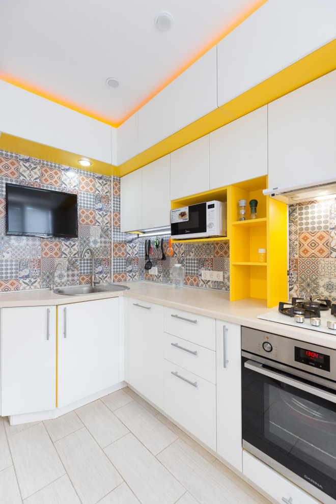 Small contemporary l-shaped separate kitchen in Other with a single-bowl sink, flat-panel cabinets, white cabinets, wood benchtops, multi-coloured splashback, ceramic splashback, stainless steel appliances, laminate floors, beige floor and beige benchtop.