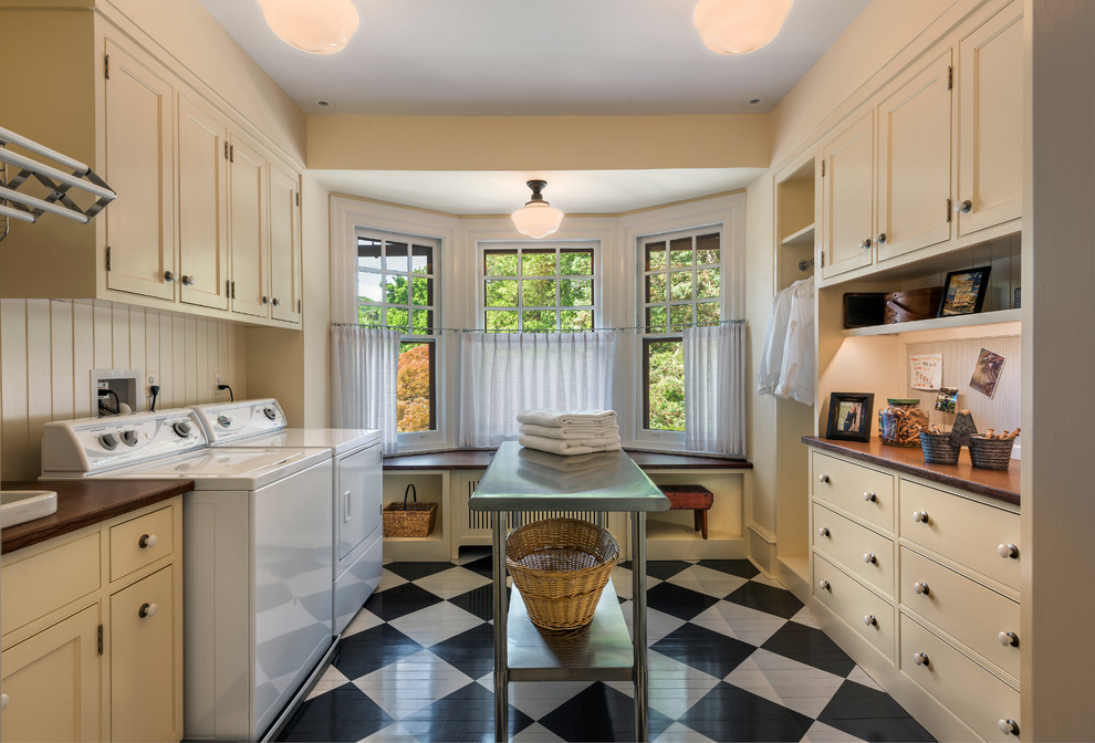 Photo of a traditional galley dedicated laundry room in Philadelphia with beaded inset cabinets, beige cabinets, beige walls, painted wood floors, a side-by-side washer and dryer and multi-coloured floor.