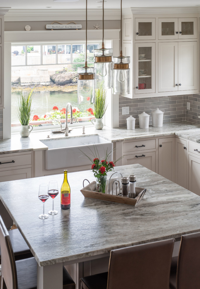 This is an example of a large transitional l-shaped eat-in kitchen in Boston with a farmhouse sink, beaded inset cabinets, white cabinets, marble benchtops, grey splashback, subway tile splashback, stainless steel appliances, with island and grey benchtop.