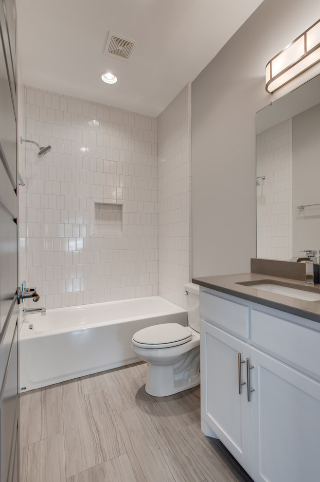 Photo of a mid-sized transitional 3/4 bathroom in Nashville with shaker cabinets, white cabinets, an alcove tub, a shower/bathtub combo, a two-piece toilet, white tile, subway tile, grey walls, porcelain floors, an undermount sink, engineered quartz benchtops, grey floor and a shower curtain.