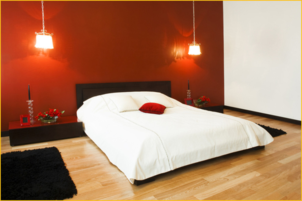 This is an example of a large asian master bedroom in Toronto with red walls, light hardwood floors and no fireplace.