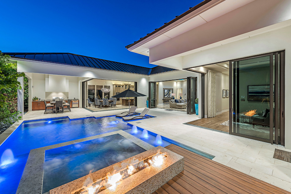 Mid-sized contemporary backyard custom-shaped pool in Miami with a hot tub and natural stone pavers.