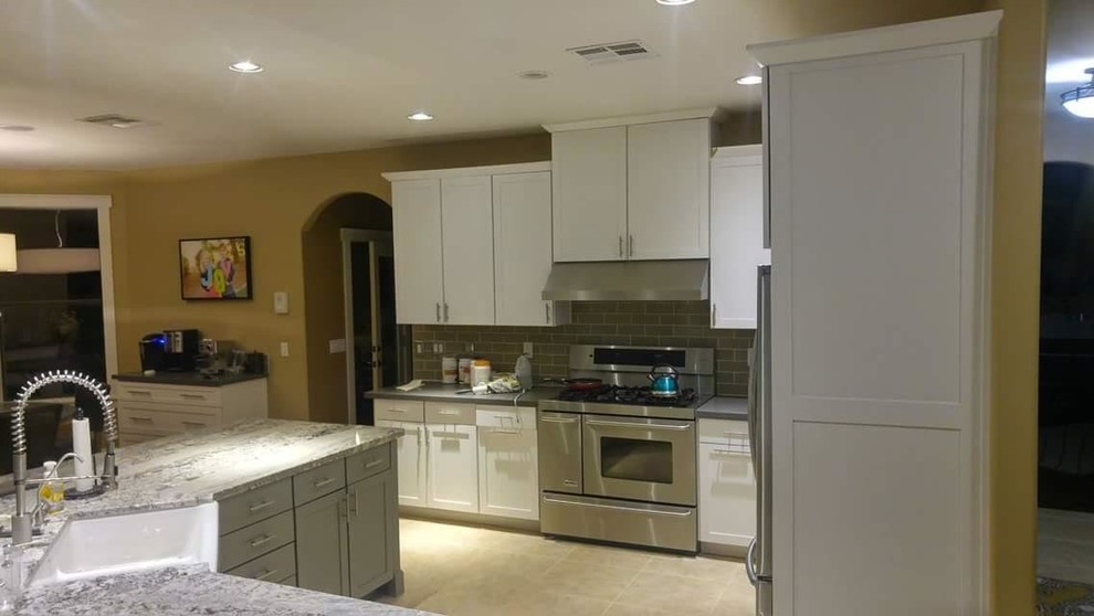 Example of a large transitional ceramic tile and beige floor open concept kitchen design in Phoenix with a farmhouse sink, shaker cabinets, white cabinets, granite countertops, brown backsplash, subway tile backsplash, stainless steel appliances and an island