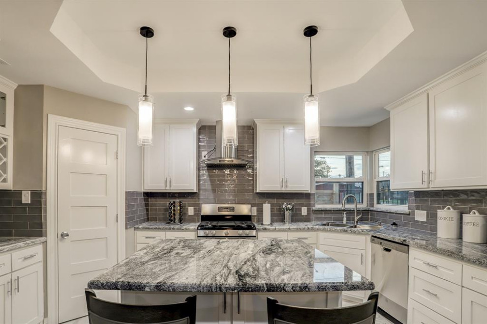 Photo of a mid-sized modern u-shaped eat-in kitchen in Houston with a drop-in sink, shaker cabinets, white cabinets, granite benchtops, grey splashback, glass tile splashback, stainless steel appliances, porcelain floors, with island, white floor and grey benchtop.