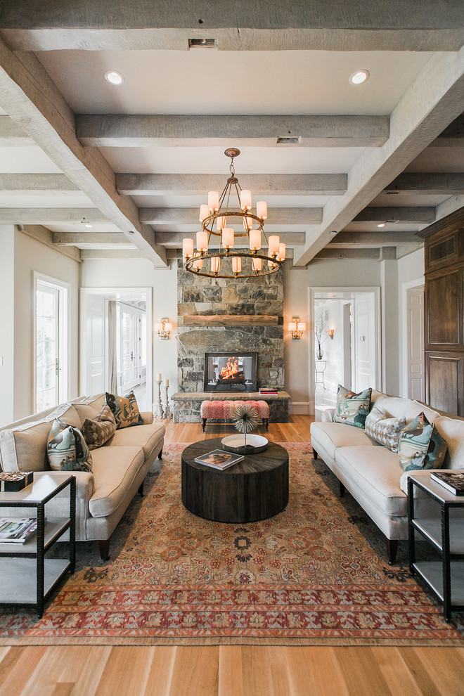 Inspiration for a large country formal enclosed living room in Baltimore with beige walls, light hardwood floors, a two-sided fireplace, a stone fireplace surround, no tv and beige floor.