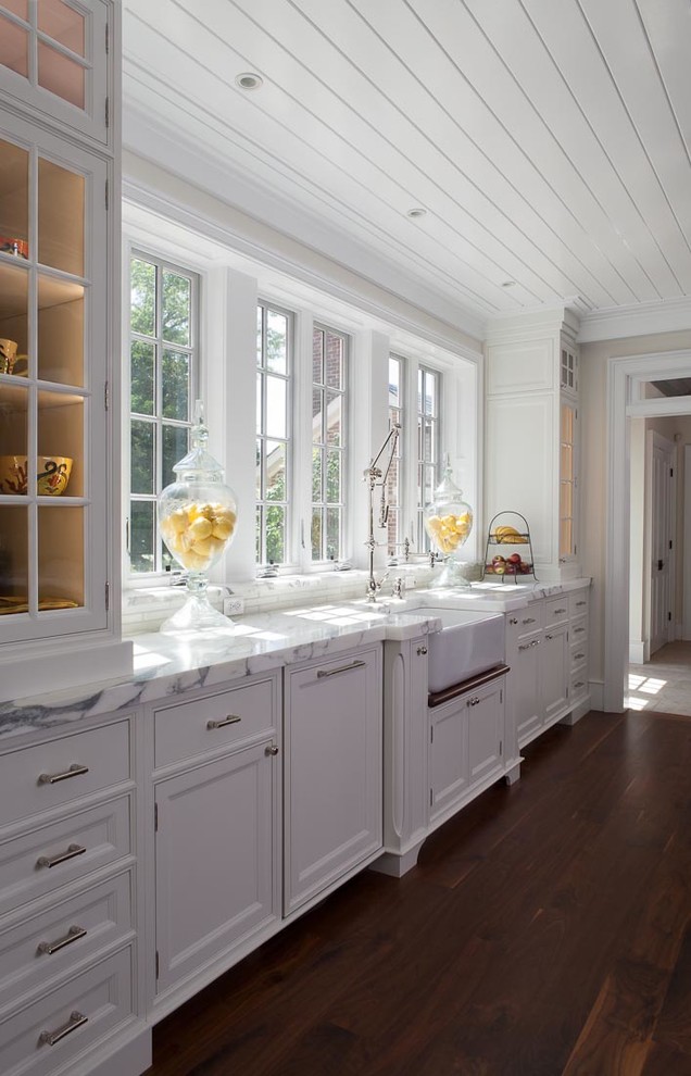Photo of a large country u-shaped open plan kitchen in DC Metro with a farmhouse sink, beaded inset cabinets, white cabinets, marble benchtops, multi-coloured splashback, stone slab splashback, panelled appliances, dark hardwood floors and multiple islands.