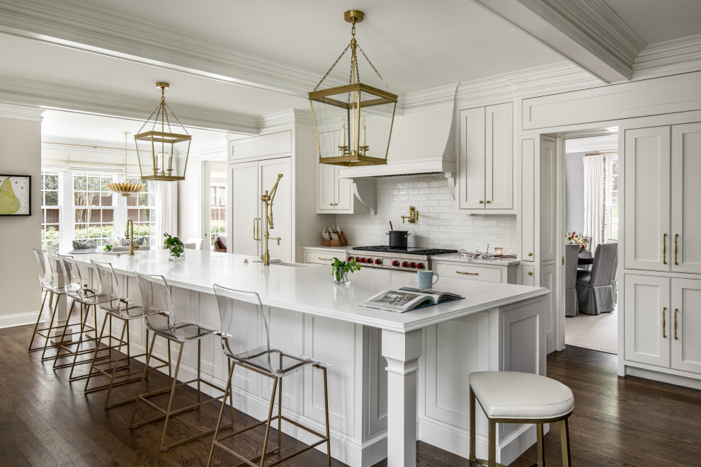 Large classic galley kitchen in Nashville with a belfast sink, beaded cabinets, white cabinets, engineered stone countertops, white splashback, porcelain splashback, integrated appliances, an island, white worktops, a coffered ceiling, dark hardwood flooring and brown floors.