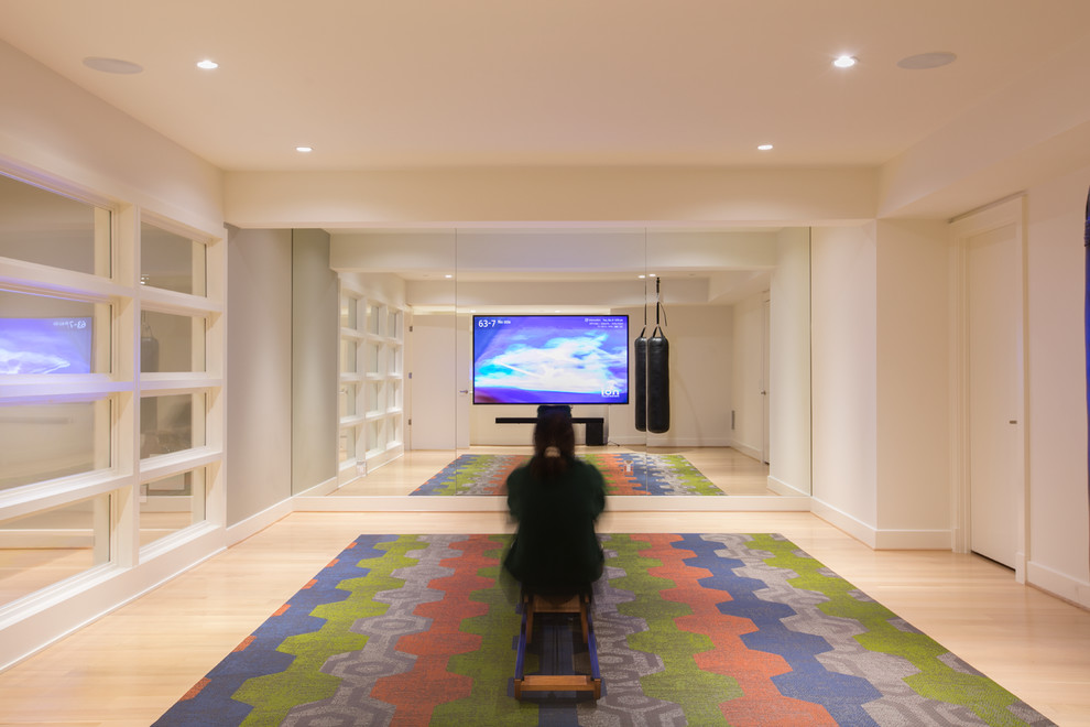 This is an example of a mid-sized modern home yoga studio in DC Metro with white walls and light hardwood floors.