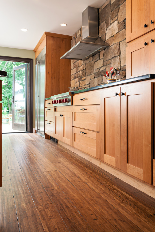 Mid-sized transitional u-shaped bamboo floor eat-in kitchen photo in Boston with an undermount sink, shaker cabinets, medium tone wood cabinets, brown backsplash, stone tile backsplash, stainless steel appliances, green walls and an island