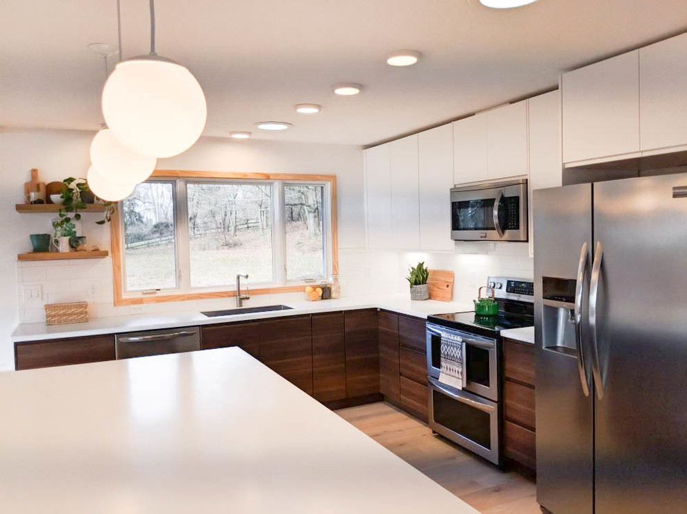 Mid-sized midcentury l-shaped eat-in kitchen in Other with flat-panel cabinets, medium wood cabinets, with island, an undermount sink, quartz benchtops, white splashback, subway tile splashback, stainless steel appliances, light hardwood floors and grey floor.