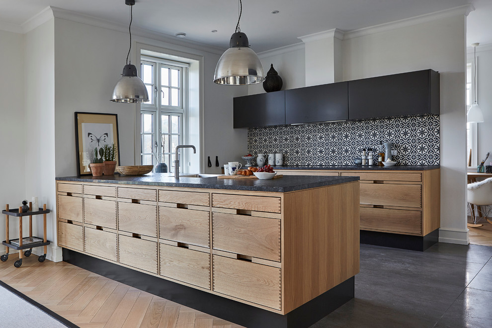 This is an example of a scandinavian kitchen in Aalborg with flat-panel cabinets, black cabinets, multi-coloured splashback, concrete floors and a peninsula.