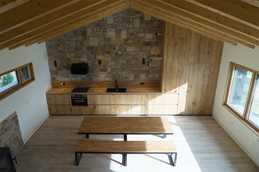 Imagen de comedor rústico pequeño abierto con paredes blancas, suelo de madera clara, todas las chimeneas, marco de chimenea de metal y vigas vistas
