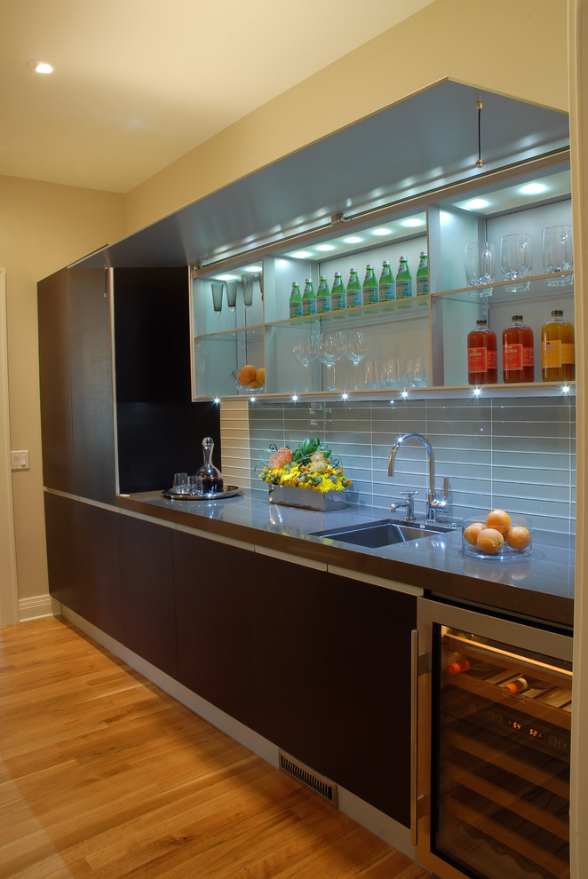 Photo of a large contemporary single-wall kitchen pantry in Minneapolis with an undermount sink, louvered cabinets, dark wood cabinets, quartz benchtops, grey splashback, glass tile splashback, stainless steel appliances, light hardwood floors, no island and brown floor.