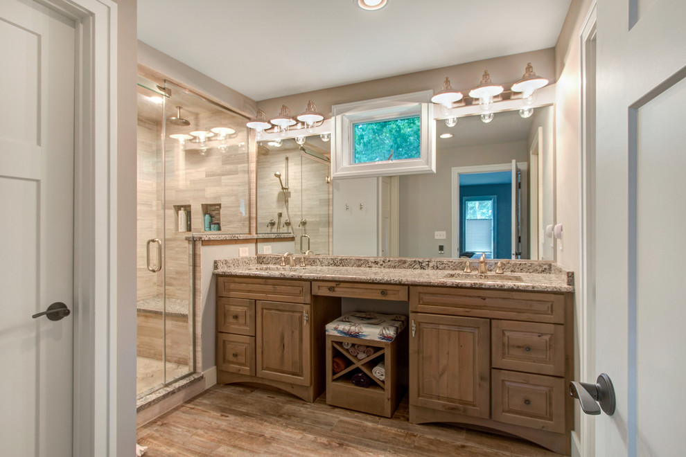 Photo of a mid-sized beach style master bathroom in Milwaukee with raised-panel cabinets, light wood cabinets, an alcove shower, beige tile, porcelain tile, beige walls, porcelain floors, an undermount sink and granite benchtops.